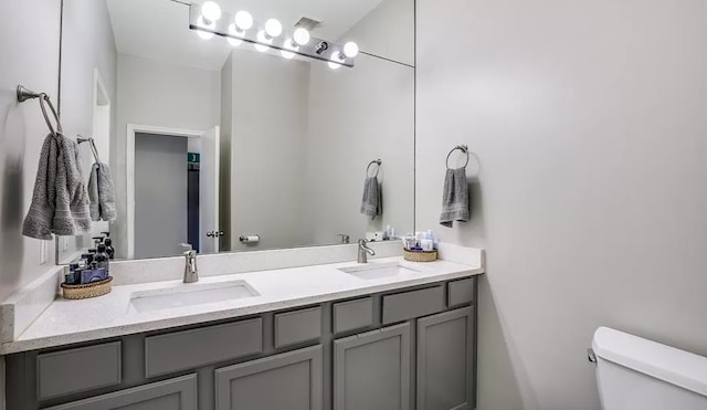 bathroom with double vanity, toilet, and a sink