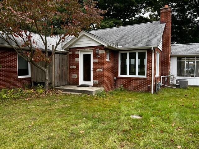 view of front of home with central air condition unit and a front yard