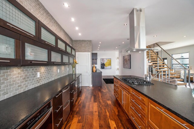 443 N Shore Dr, South Haven, MI 49090 - kitchen featuring island exhaust hood, stainless steel gas cooktop, dark wood-style floors, glass insert cabinets, and tasteful backsplash