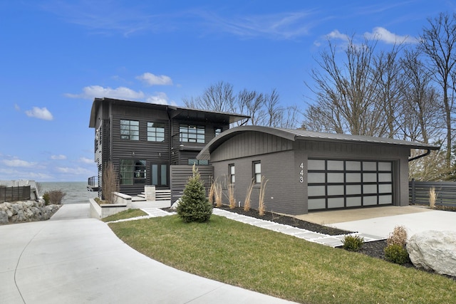 443 N Shore Dr, South Haven, MI 49090 - contemporary house featuring concrete driveway, an attached garage, and brick siding