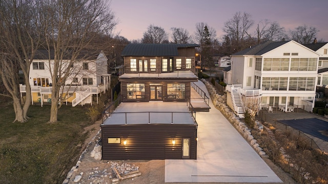 443 N Shore Dr, South Haven, MI 49090 - back of house at dusk with a balcony, a sunroom, and stairs
