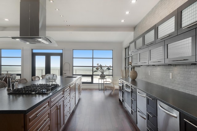 443 N Shore Dr, South Haven, MI 49090 - kitchen featuring island range hood, a sink, dark countertops, stainless steel appliances, and decorative backsplash