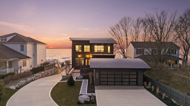 443 N Shore Dr, South Haven, MI 49090 - view of front of property with a water view, concrete driveway, stairs, a garage, and metal roof