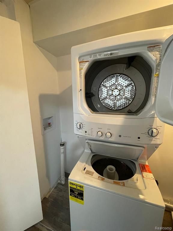 washroom featuring stacked washer / dryer and dark hardwood / wood-style floors