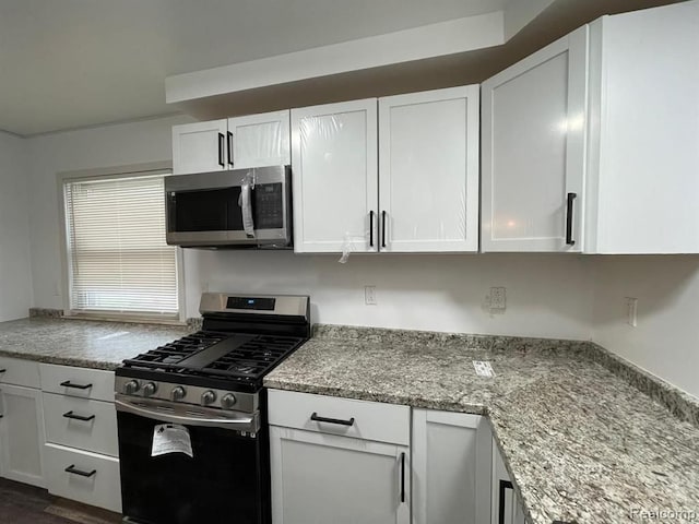 kitchen with white cabinets, appliances with stainless steel finishes, and light stone countertops