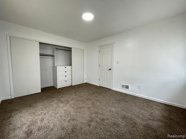 unfurnished bedroom with a closet and dark colored carpet