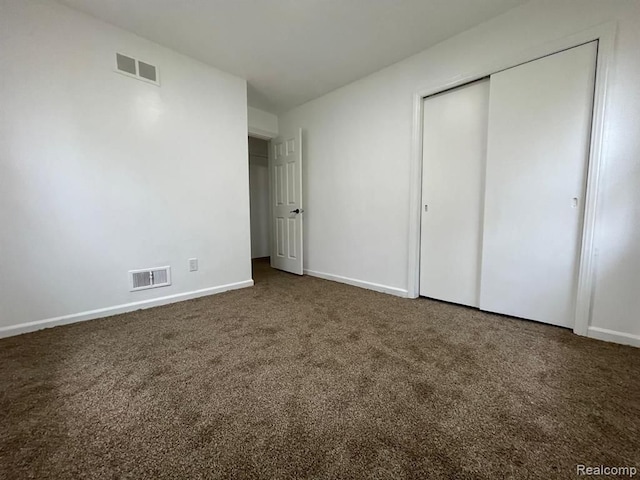 unfurnished bedroom with a closet and dark carpet