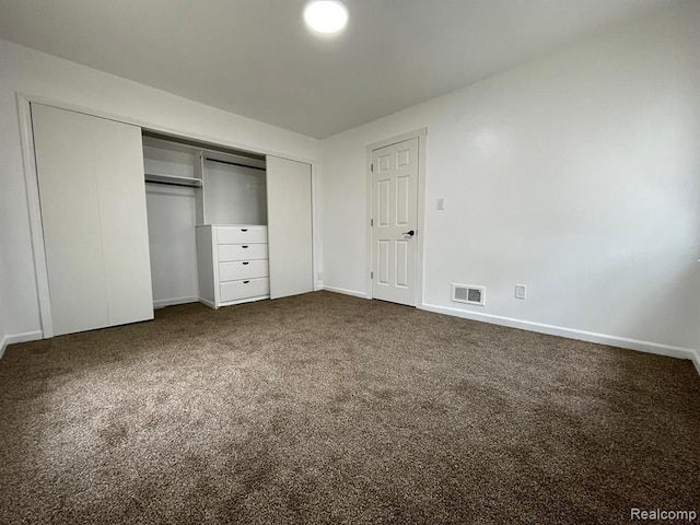 unfurnished bedroom with dark carpet and a closet