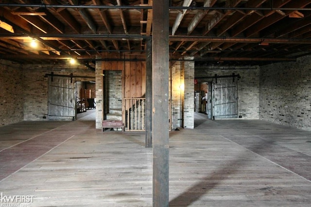 basement with a barn door and wood-type flooring