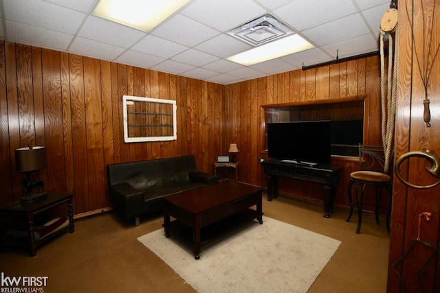 living room featuring carpet, a drop ceiling, and wood walls