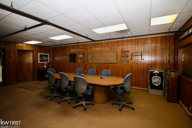 office area with carpet flooring, a paneled ceiling, and wood walls