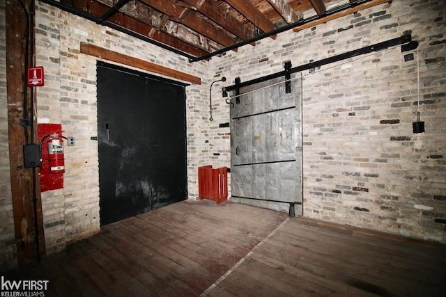 empty room with hardwood / wood-style flooring and brick wall