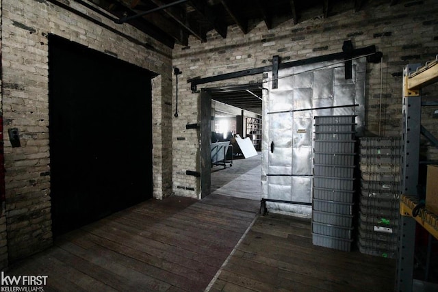 hall with dark hardwood / wood-style flooring and brick wall