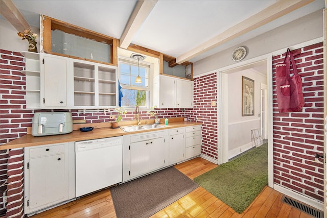 kitchen featuring light wood-type flooring, sink, dishwasher, white cabinetry, and hanging light fixtures