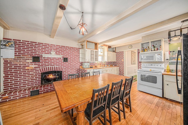 kitchen featuring light wood-type flooring, a brick fireplace, white appliances, decorative light fixtures, and beamed ceiling