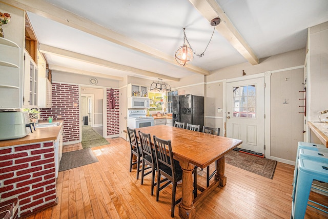 dining space featuring beam ceiling and light wood-type flooring