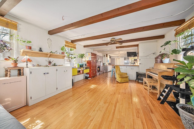 living room with ceiling fan, beamed ceiling, and light wood-type flooring