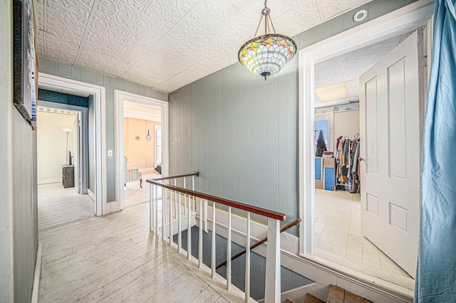 hallway with wood walls and light hardwood / wood-style flooring