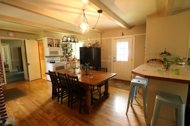 dining area with beamed ceiling and light hardwood / wood-style floors