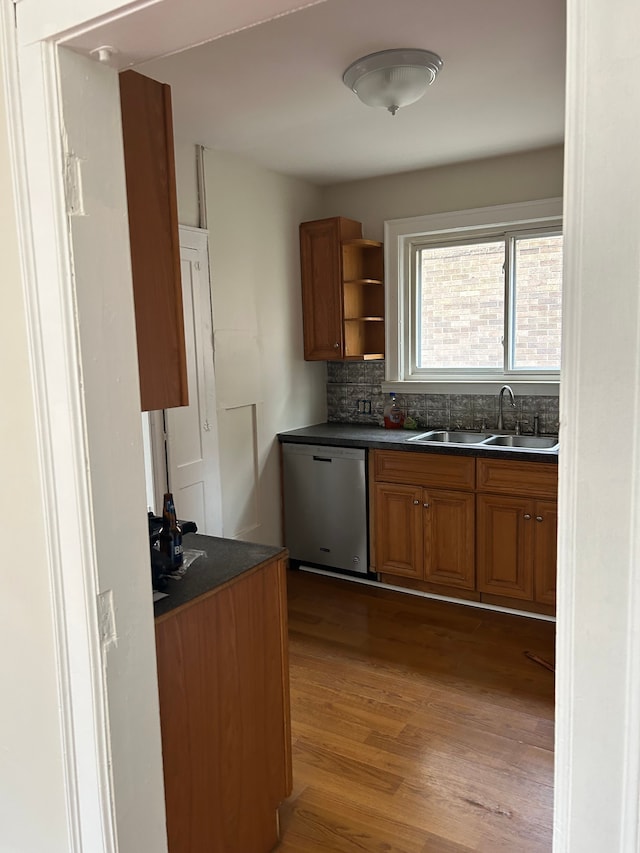 kitchen with backsplash, dishwasher, sink, and light hardwood / wood-style flooring