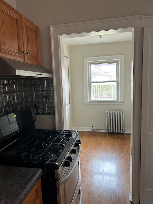 kitchen with light wood-type flooring, extractor fan, radiator, and stainless steel gas range