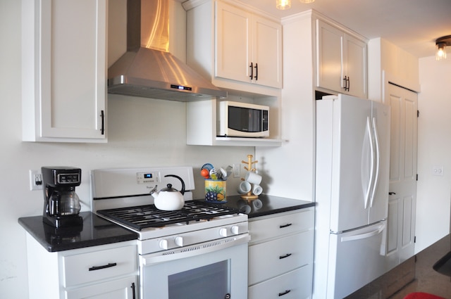 kitchen with white cabinets, white appliances, and wall chimney range hood