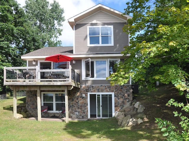 rear view of house featuring a wooden deck and a yard