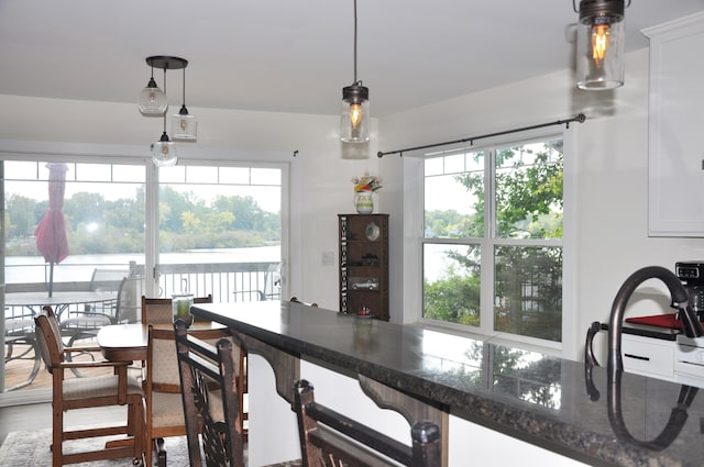 kitchen with plenty of natural light, white cabinets, pendant lighting, and wood-type flooring