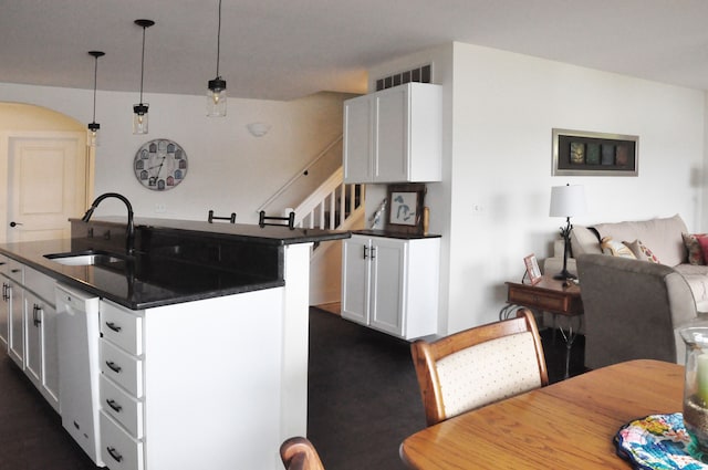 kitchen with dishwasher, sink, dark colored carpet, pendant lighting, and white cabinets