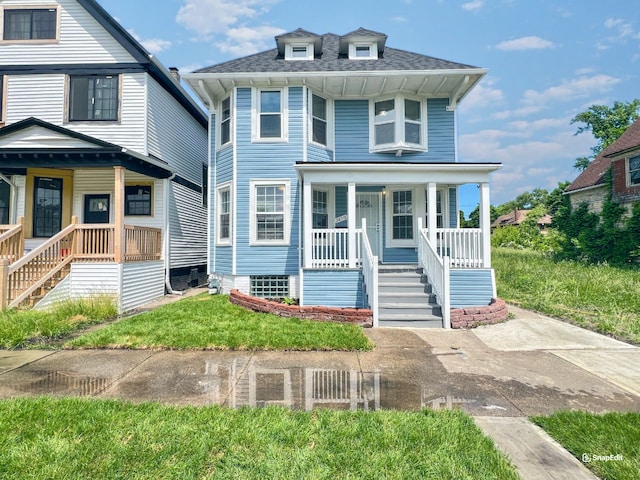 traditional style home featuring a front lawn, covered porch, stairs, and a shingled roof