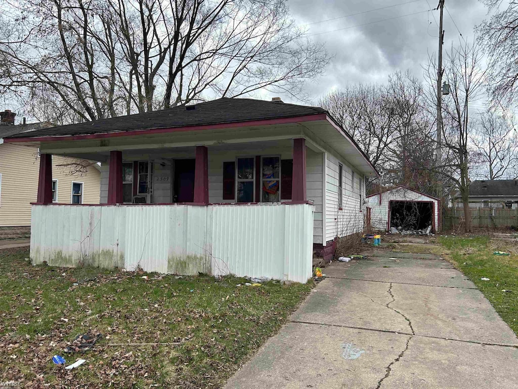 view of side of home with a yard, covered porch, and an outdoor structure