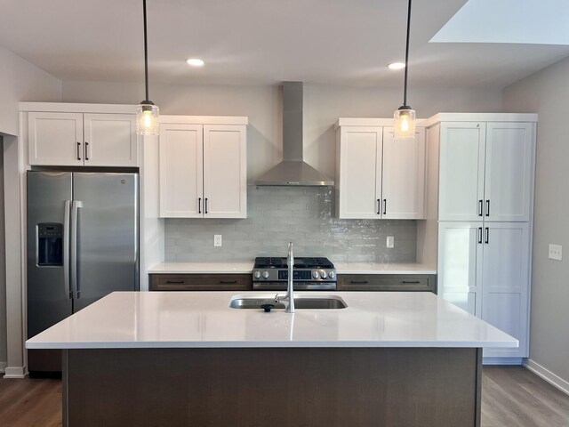 kitchen featuring stainless steel appliances, a sink, light countertops, wall chimney range hood, and tasteful backsplash