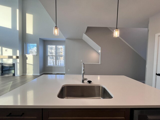 kitchen featuring decorative light fixtures, open floor plan, a sink, and light countertops