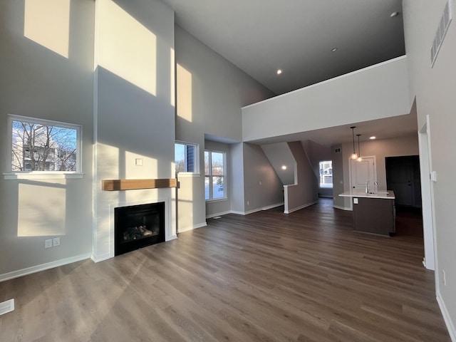 unfurnished living room with a healthy amount of sunlight, a fireplace, visible vents, and dark wood finished floors