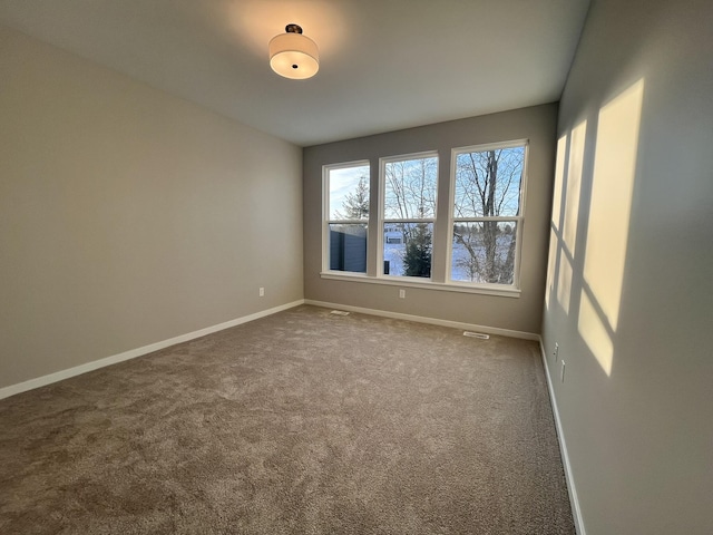 carpeted spare room featuring visible vents and baseboards