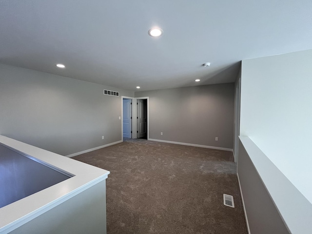 empty room featuring visible vents, dark colored carpet, and recessed lighting