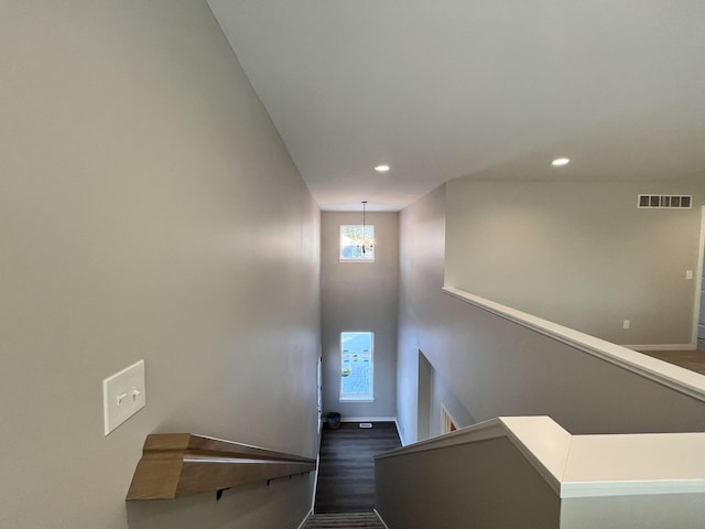 stairway featuring an inviting chandelier, wood finished floors, visible vents, and recessed lighting