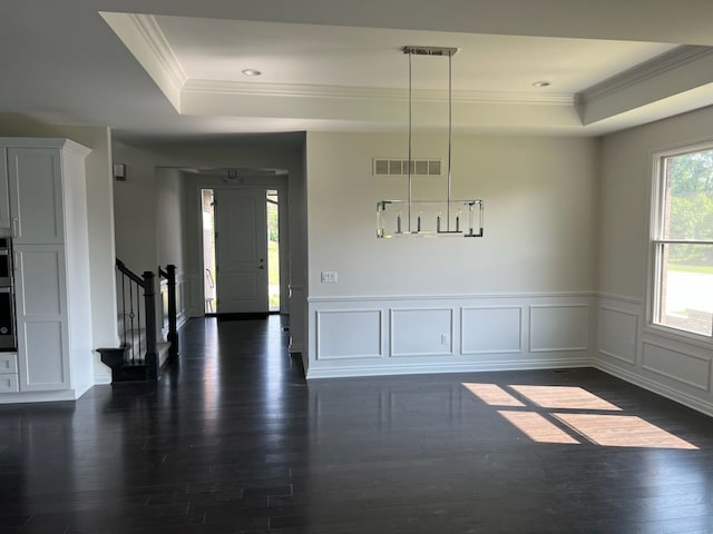 unfurnished dining area featuring dark hardwood / wood-style flooring, a raised ceiling, and crown molding