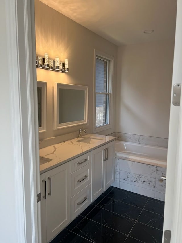 bathroom with vanity and tiled bath