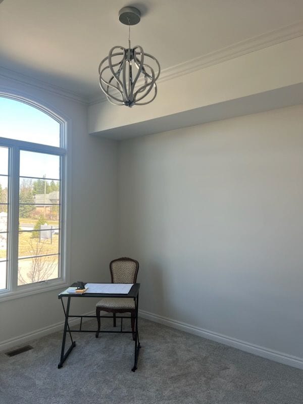 living area featuring dark colored carpet, crown molding, and a notable chandelier