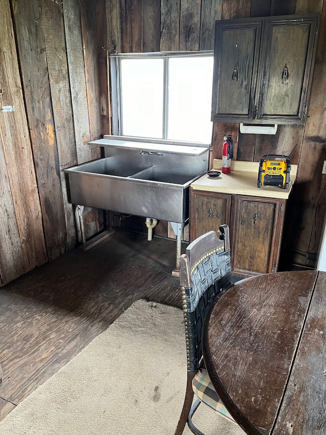 kitchen featuring dark brown cabinetry, sink, and wooden walls