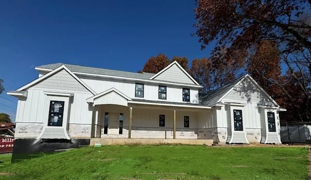 modern farmhouse style home with covered porch and a front lawn