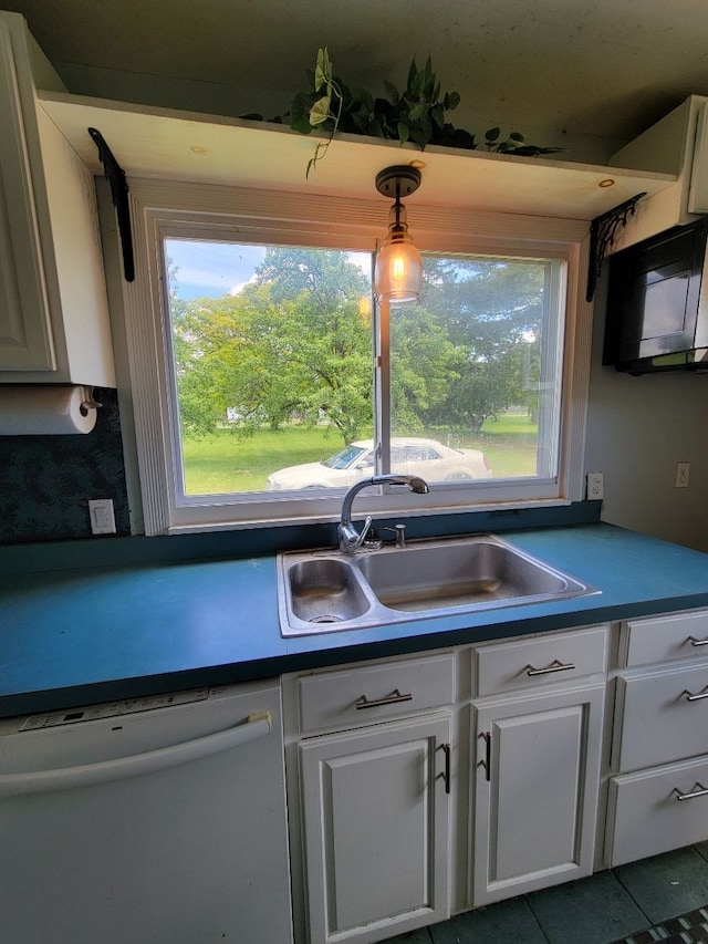 kitchen featuring white dishwasher, white cabinets, sink, hanging light fixtures, and tile patterned flooring