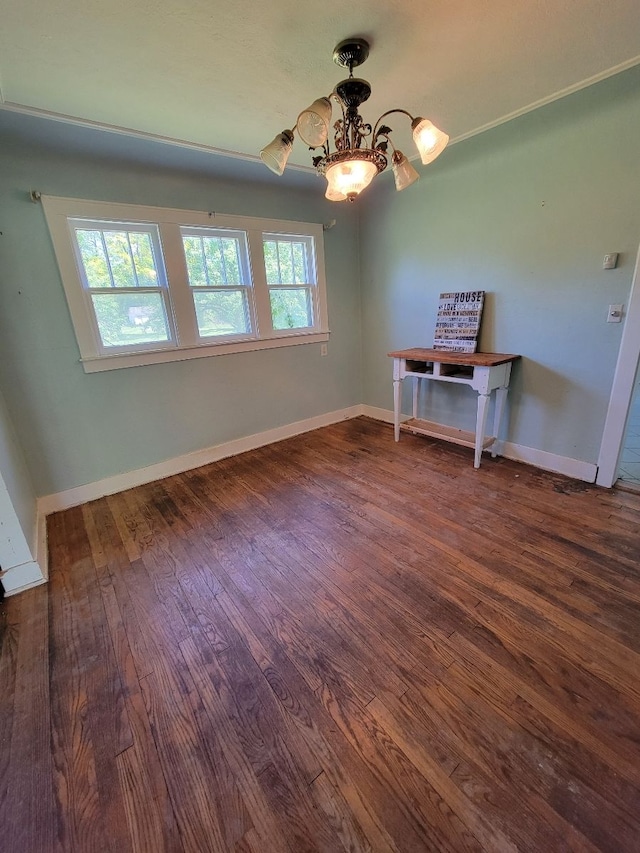 spare room with dark hardwood / wood-style flooring and a chandelier