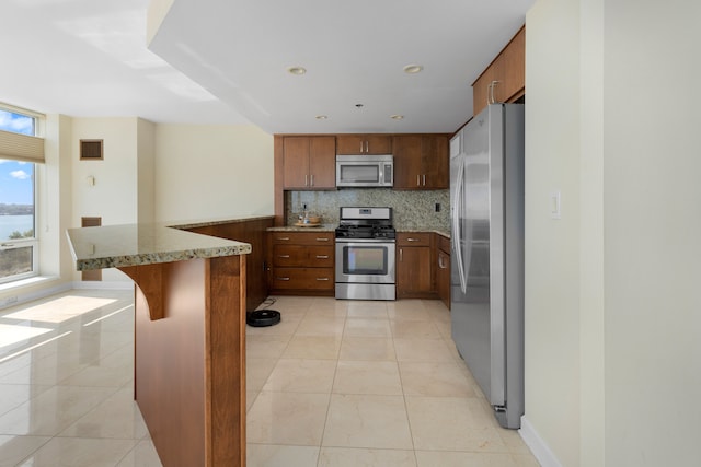 kitchen featuring a breakfast bar area, light tile patterned floors, tasteful backsplash, kitchen peninsula, and stainless steel appliances