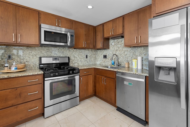 kitchen featuring light stone countertops, sink, appliances with stainless steel finishes, and tasteful backsplash