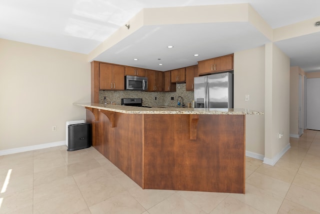 kitchen with sink, light stone countertops, tasteful backsplash, kitchen peninsula, and stainless steel appliances