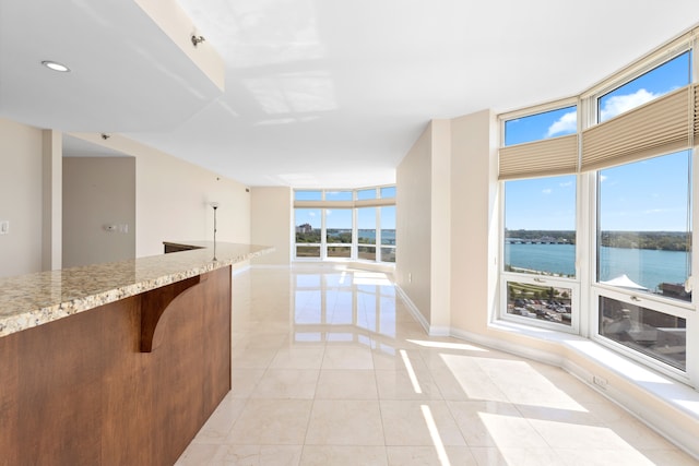 empty room with plenty of natural light, a water view, and light tile patterned floors