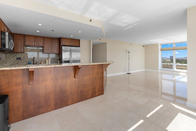 kitchen with decorative backsplash, kitchen peninsula, a breakfast bar, stainless steel appliances, and sink