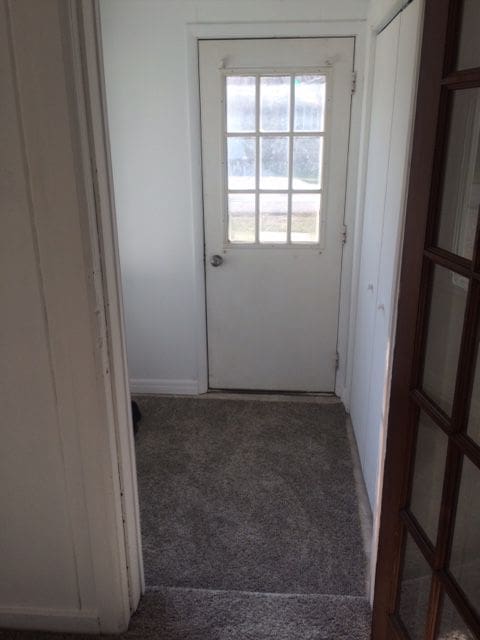 doorway to outside with dark colored carpet